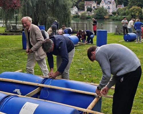 Participants assemblant un radeau avec bidons et bois avant la mise &agrave; l&rsquo;eau